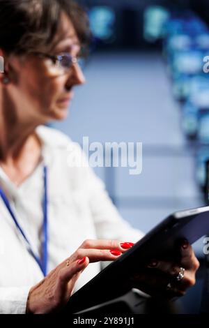 Close up of octogenarian engineer writing script code in data center on laptop terminal. Precise manager doing maintenance work in server room, updating mainframes software to prevent malfunctions Stock Photo