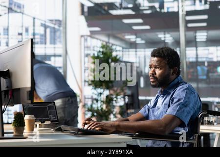 Person with paraplegia conducting code review to fix bugs, identifying potential performance and technical issues with company software. IT worker with disability in wheelchair optimizing code Stock Photo