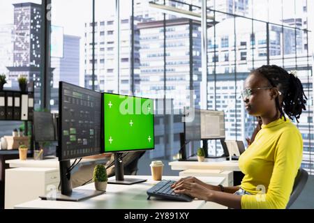 Admin looking at isolated screen computer, managing cloud computing resources and platforms to train machine learning models. Woman monitoring and maintaining company systems using chroma key PC Stock Photo