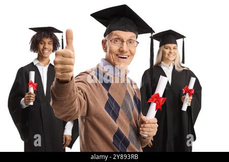 Senior man with graduate students in gowns holding a diploma and gesturing thumbs up isolated on white background Stock Photo