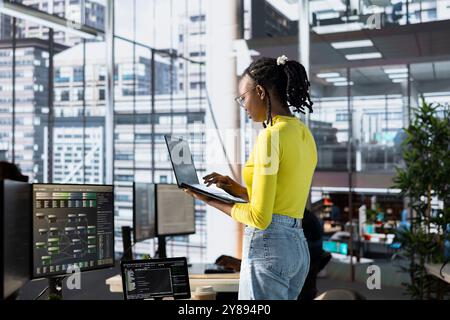 Machine learning infrastructure technician using laptop to develop algorithms that enable machines to learn from data. Admin in office training large scale deep learning models using notebook Stock Photo