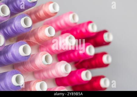 Multi-colored threads in spools and bobbins for sewing in a sewing workshop Stock Photo