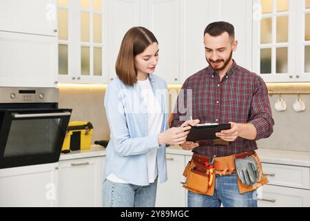 Woman and repairman signing documents near oven in kitchen Stock Photo
