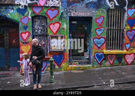 Man and his daughter walking next to a graffiti wall in Hosier lane in Melbourne, Australia Stock Photo