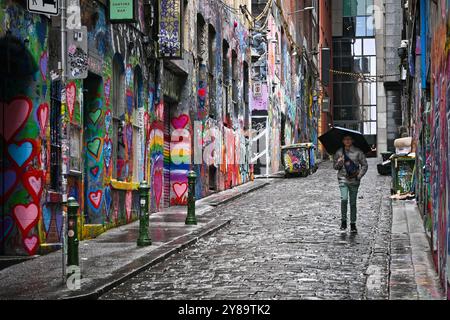 A man with an umbrella walking in Hosier lane, a famous graffiti street in Melbourne, Australia Stock Photo