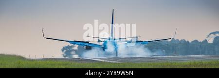 Balikpapan, Indonesia - September 26th, 2024. a Garuda Indonesia Boeing 737-8U3 touches down on the runway, kicking up a cloud of dust. The plane's la Stock Photo