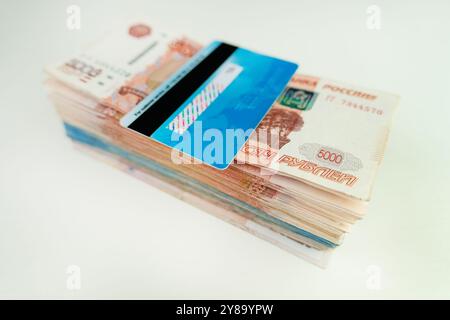 Credit cards and ruble bills isolated on white background. a blue plastic bank card is lying on a pile of Russian ruble. Payment by credit card. Stock Photo