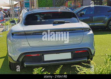 The back of a silver porsche taycan 4s electric car parked on a grass field Stock Photo