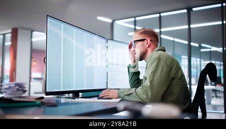 Unhappy Sad Developer Programmer Man In Stress Coding Software On Computer Stock Photo