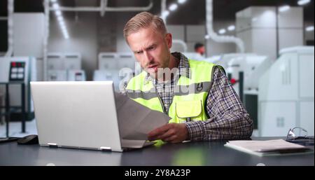 Shocked Factory Engineer Reading Document At Desk In Office Stock Photo