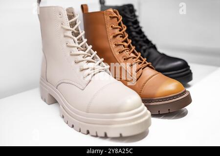 Stylish leather boots on a shelf. Store with fashionable womens shoes. Combat boots Female classic spring autumn boots. Leather laced casual footwear. Stock Photo