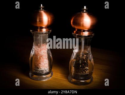 Set of copper salt and pepper grinders isolated on a wooden table Stock Photo