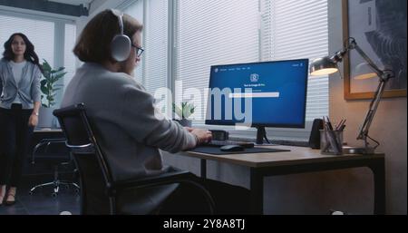 Adult man in headphones enters prompt in AI image generator app on PC. Advanced artificial intelligence chatbot generate detailed image portrait of sci-fi robot. From text prompt to generated photo. Stock Photo