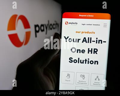 Person holding cellphone with webpage of software company Paylocity Holding Corporation on screen with logo. Focus on center of phone display. Stock Photo