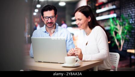 Coworkers Using Technology Lifestyle. Man And Woman Drinking Coffee In Cafe Stock Photo