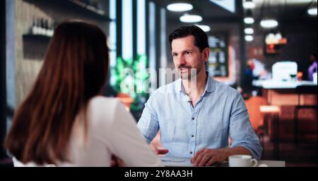 Laughing Male And Female Sitting In Cafe Drinking Coffee And Talking Stock Photo
