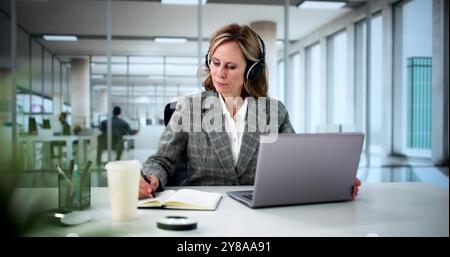 Student Embraces Online Studying With Laptop And Headphones, Enjoying Webinars On Education And Preparing For Tests Stock Photo