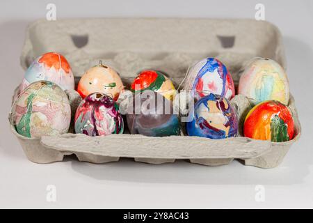 A close-up view of a variety of brightly colored, hand-painted Easter eggs arranged in a paper egg carton Stock Photo