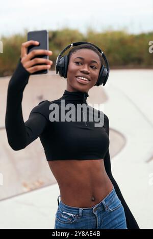ethnic female in headset taking selfie on phone Stock Photo