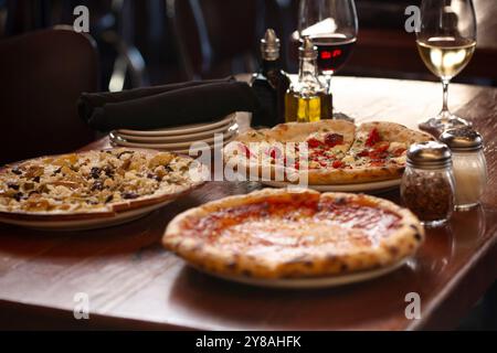 A trio of pizzas and flatbreads on wood table Stock Photo