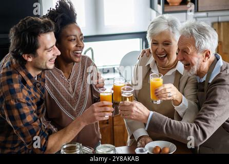 Multi generation multiethnic family having fun, talking around a festive kitchen table. Stock Photo