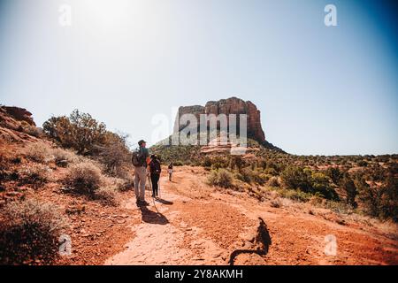 Hikers walking on a red desert trail with a distinctive butte in Stock Photo