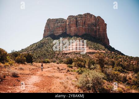 Hikers walking on a red desert trail with a distinctive butte in Stock Photo