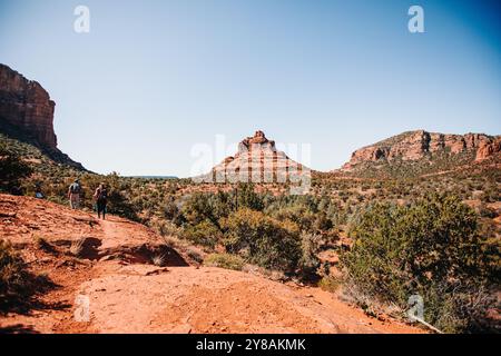 Hikers walking on a red desert trail with a distinctive butte in Stock Photo