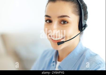 Close-up of charming successful caucasian brunette woman with wireless headset, working in customer support service or helpline, female call center agent, business advicer, smiles at camera Stock Photo