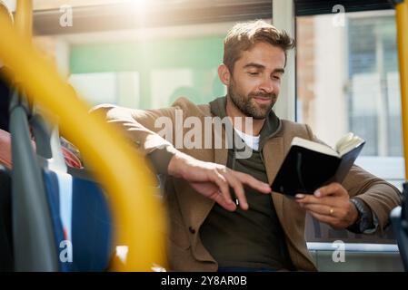 Bus, travel and man by window with book for journey, commute and passenger in city. Public transport, station and person on vehicle with literature Stock Photo