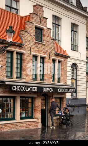 Belgium, Flanders, Bruges, Eirmarkt, Chocolatier Dumon, attractive brick built chocolate shop in wet weather Stock Photo