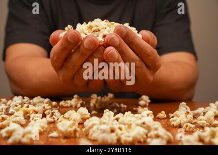 Popcorn scattered on table surface. Delicious snack to eat in the cinema. Flavored spicy popcorn in man's hands. Salted popcorn. Popcorn. Fast food Stock Photo