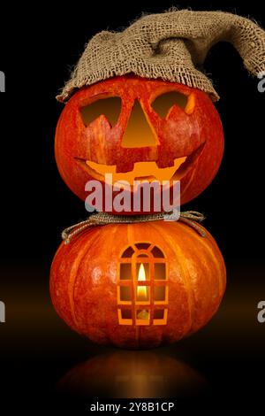 A creative display of two stacked pumpkins, one featuring a happy face and a window, illuminated from within, perfect for Halloween celebrations this Stock Photo