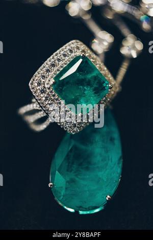 Emeralds close-up in jewelry. Beautiful ring of earrings with green Emerald and Diamonds gemstones. Luxury female jewelry, on a black background close Stock Photo