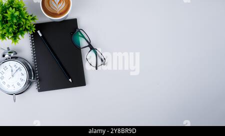 Top view white workspace office desk with office supplies. Flat lay work table with black notebook, Green leaf and coffee cup, Copy space for your adv Stock Photo