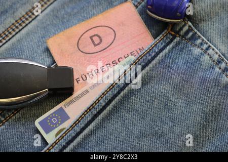 an old and a new German driving license in a trouser pocket and a car key Stock Photo