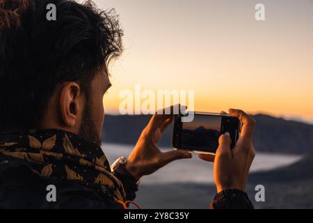 Tourist capturing memories through a photography of moon like landscape of Bromo volcano at sunrise with a dramatic sky in Java, Indonesia Stock Photo