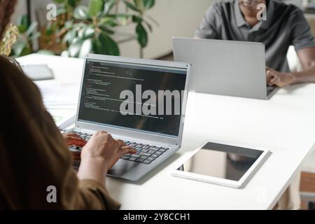 Medium close up of unrecognizable female worker sitting at work desk and writing code in modern office Stock Photo