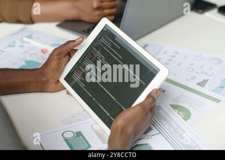 High angle shot of unrecognizable male hands holding white tablet with codes on screen Stock Photo