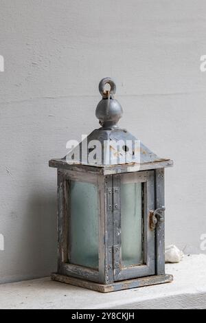 old rusty metal lantern on a shelf, corroded old fashioned style hanging lamp with glass sides on a white background Stock Photo