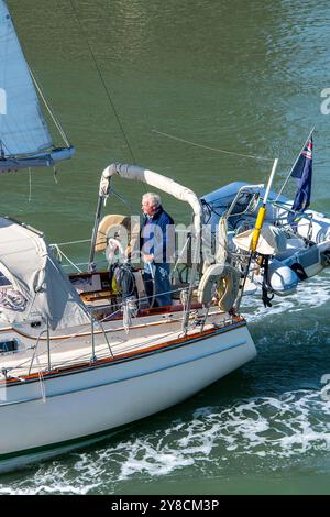 older or middle-aged man helming steering a large sailing yacht alone, older man enjoying his retirement on his sailing boat. Stock Photo
