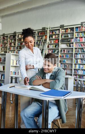 Student and his teacher actively discuss and collaborate on a study project in a lively library setting. Stock Photo