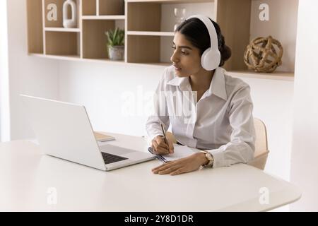 Young Indian woman in headset engaged in e-learning via pc Stock Photo