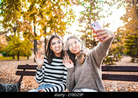 Two Women Sitting on a Bench Taking a Selfie Stock Photo