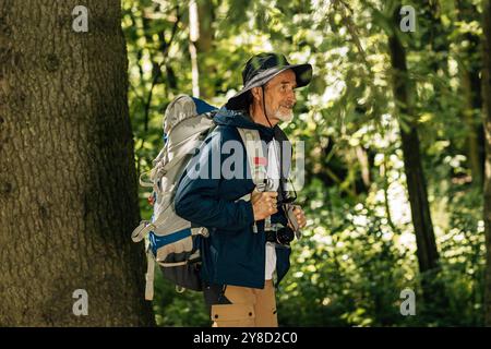 Senior male with backpack and hiking clothes walking in forest Senior male with backpack and hiking clothes walking in forest Copyright: xxArtemxVarni Stock Photo