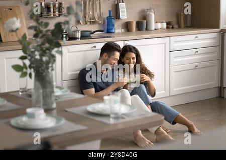 Cheerful positive young romantic couple sitting on heating floor Stock Photo