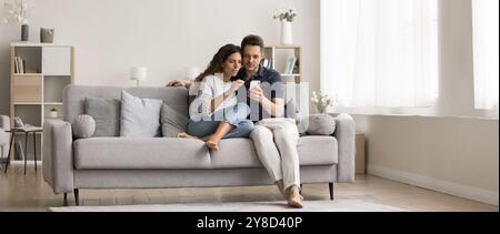 Young couple of homeowners sitting on cozy couch Stock Photo