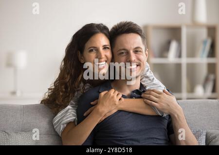 Happy beautiful young loving wife hugging cheerful handsome husband Stock Photo