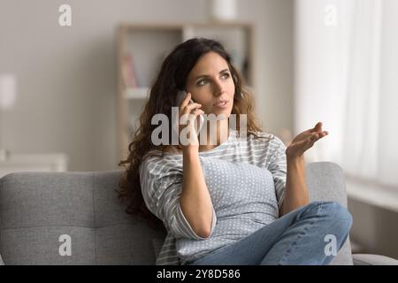 Pretty young Latin woman speaking on mobile phone at home Stock Photo