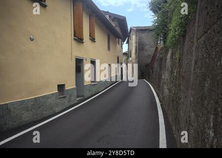 Narrow street bordered by houses in a town in the mountains on a cloudy day Stock Photo